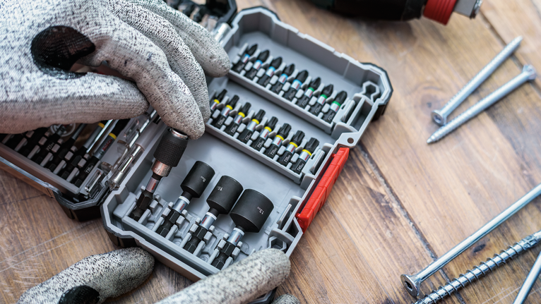 佩戴安全设备的人员从有序的盒子中选择一个螺丝刀头。