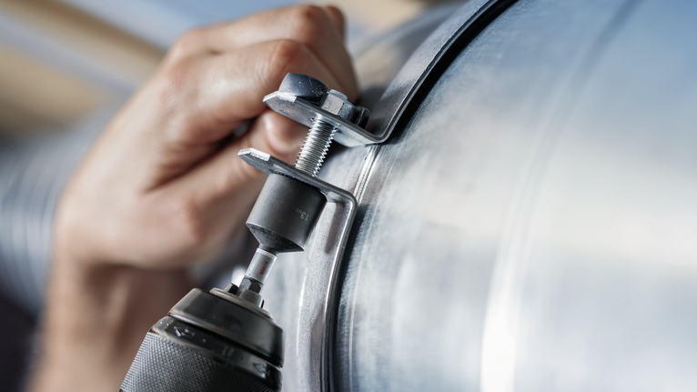 人员使用电动工具将金属夹固定到管道上。