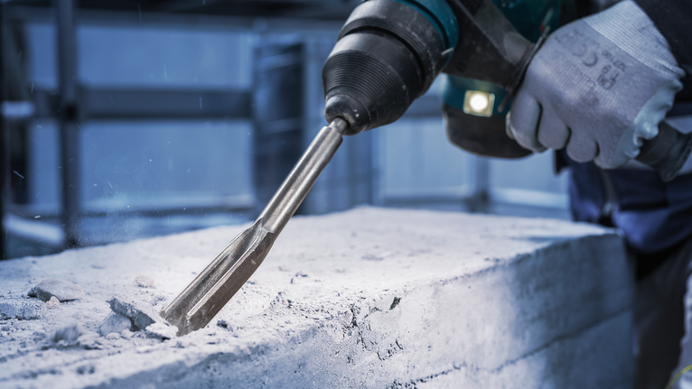 佩戴安全设备的人员使用旋转锤凿混凝土。.