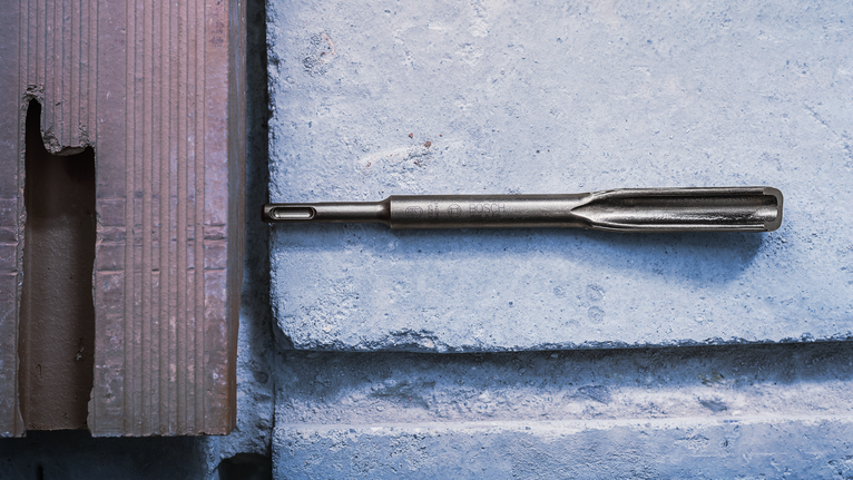 凿子钻头放置在混凝土块表面上。