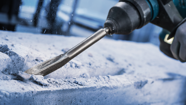 佩戴安全设备的人员使用旋转锤凿混凝土。