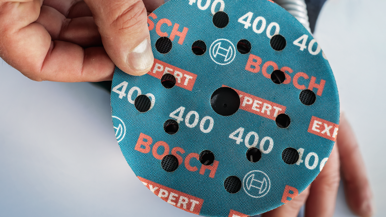 人员将圆形磨料砂轮放置在工具上。.