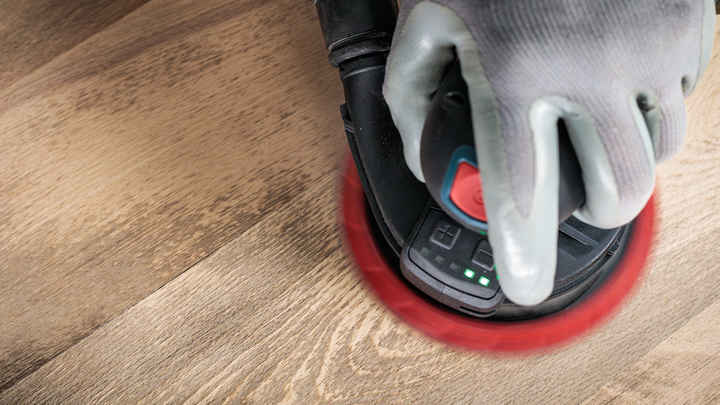 工人佩戴安全设备，用手持式电动砂光机打磨木质表面。.