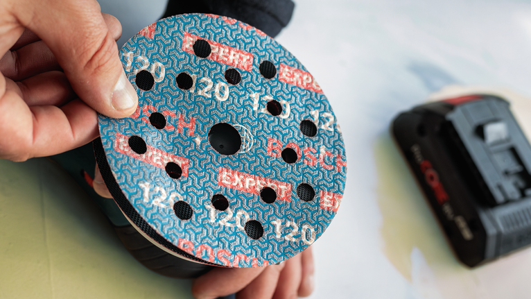 人员将砂磨盘安装到电动砂磨机上。