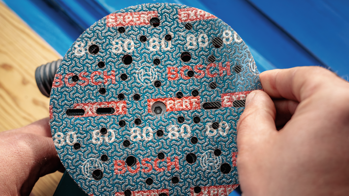 一名工人将砂轮安装到电动砂光机上。