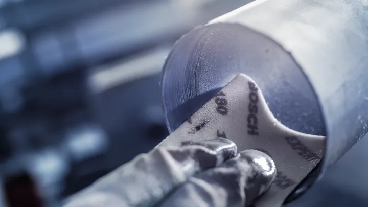 佩戴安全设备的人员正在打磨金属管道内部。