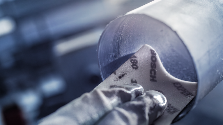 佩戴安全设备的人员正在打磨金属管道内部。