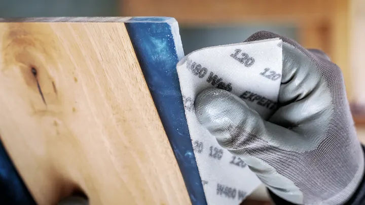 穿着安全设备的人员正在打磨木质表面。