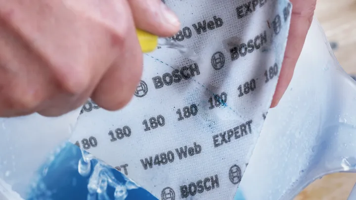 佩戴安全设备的人员将砂纸浸湿并擦洗在容器中。