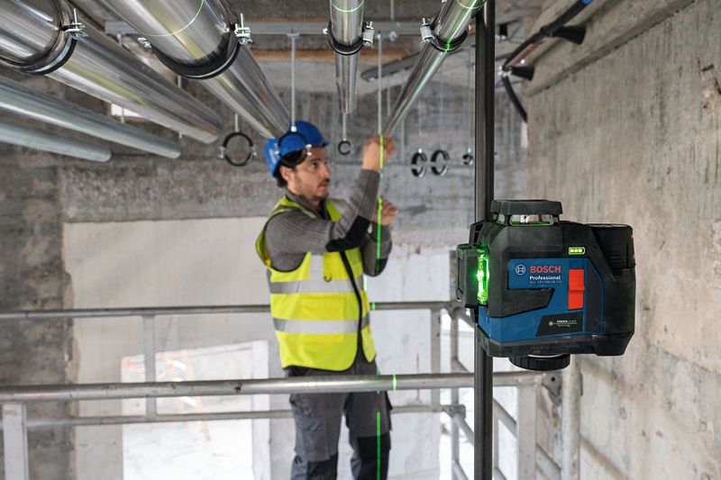 一名佩戴安全设备的人员使用激光调平工具对准管道。.