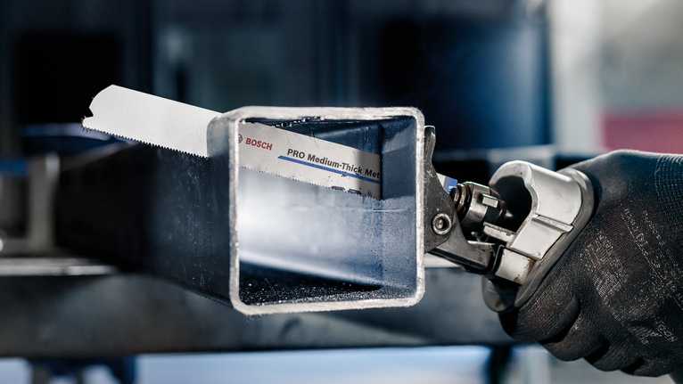 佩戴安全设备的人员用电锯切割金属方管。