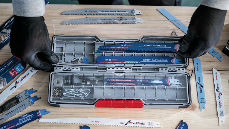 佩戴安全设备的人员将各种锯片和螺丝整理到工具箱中。