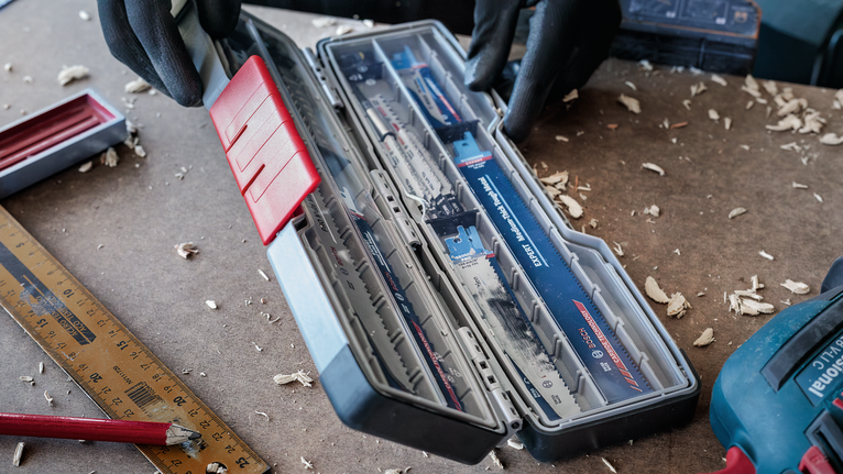 佩戴安全设备的人员在工作台上打开锯片盒。