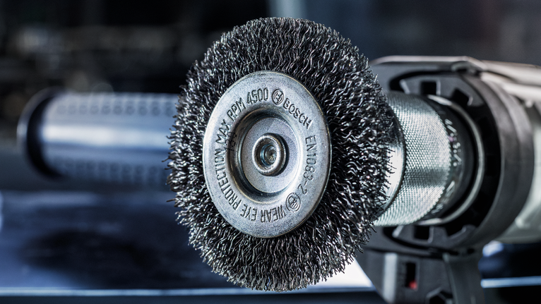 车间内安装在电动工具上的钢丝刷轮的特写。