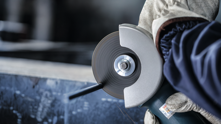 佩戴安全设备的人员使用磨床切割金属。