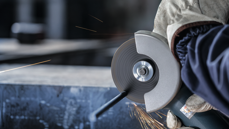 佩戴安全设备的人研磨金属，产生火花。