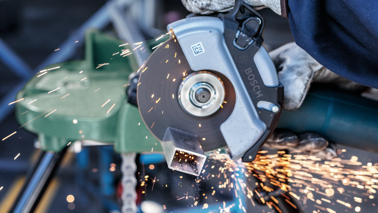 佩戴安全设备的人用圆锯切割金属管，产生火花。