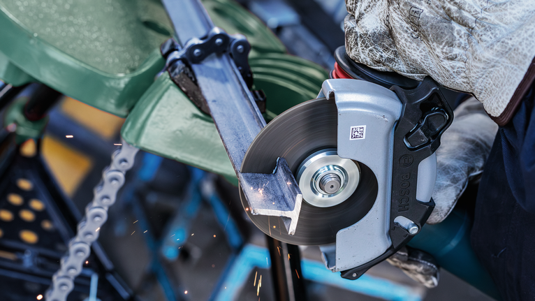 佩戴安全设备的人员用圆锯切割金属管。