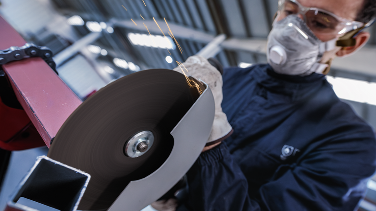 佩戴安全设备的人员使用旋转电动工具切割金属。