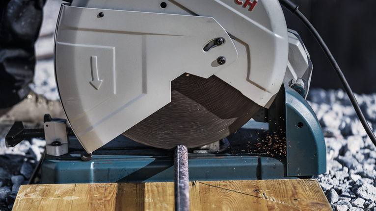 金属切断锯切断了一根钢棒，火花飞溅到木板上。