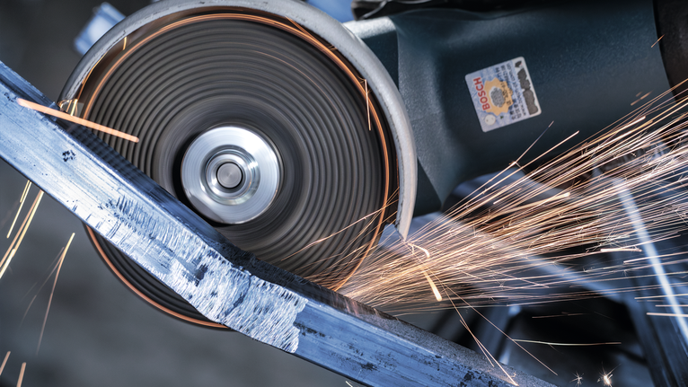 角磨机切割金属棒，产生明亮的火花。