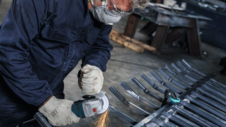 佩戴安全设备的人员使用角磨机切割金属门。