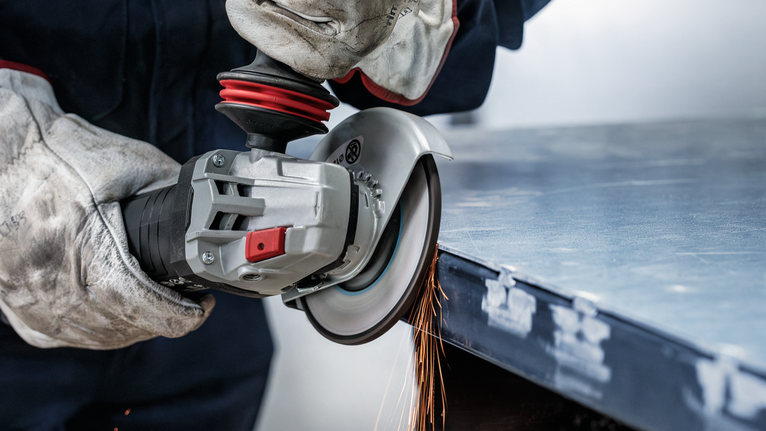 佩戴安全设备的人研磨金属，产生火花。