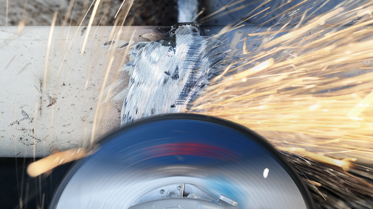 研磨工具打磨金属管，迸发出明亮的火花。