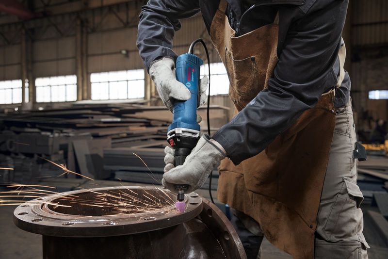 佩戴安全设备的人用直磨机打磨金属，产生火花。.