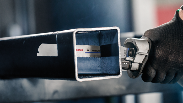 佩戴安全设备的人员使用往复锯切割金属方管。