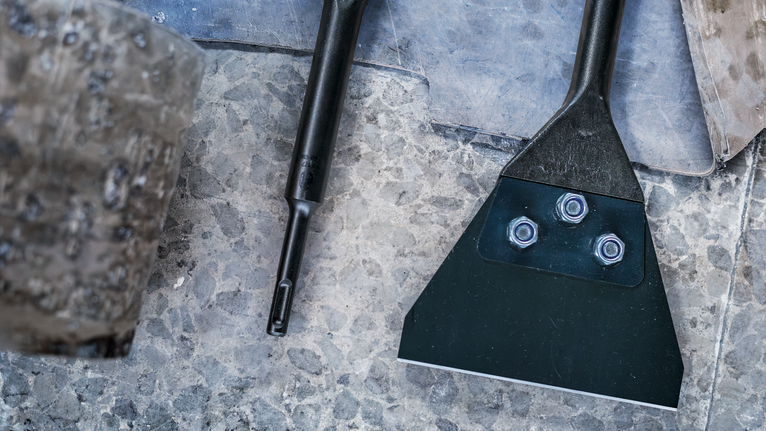 凿子附件和工具放在石地板上，旁边是一把磨损的木槌。