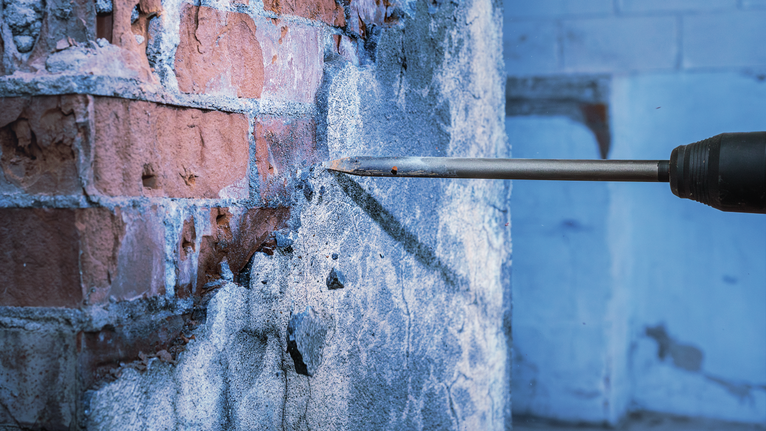 用钻凿将砖墙上的混凝土凿破。.