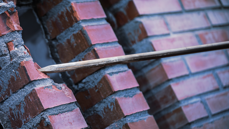 尖头凿子凿穿红砖墙。