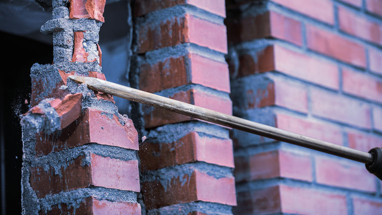 拆除过程中用凿子工具打破红砖墙。