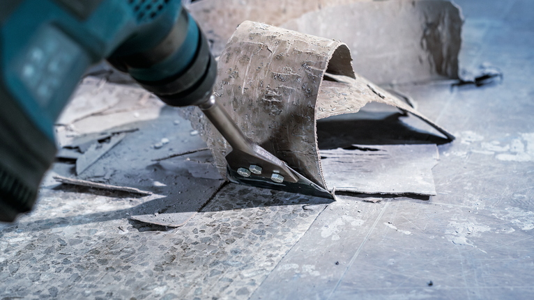 带有凿子附件的电动工具可从坚硬表面去除旧地板。