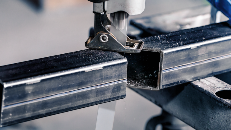 拼图锯在工作台上切割金属矩形管。