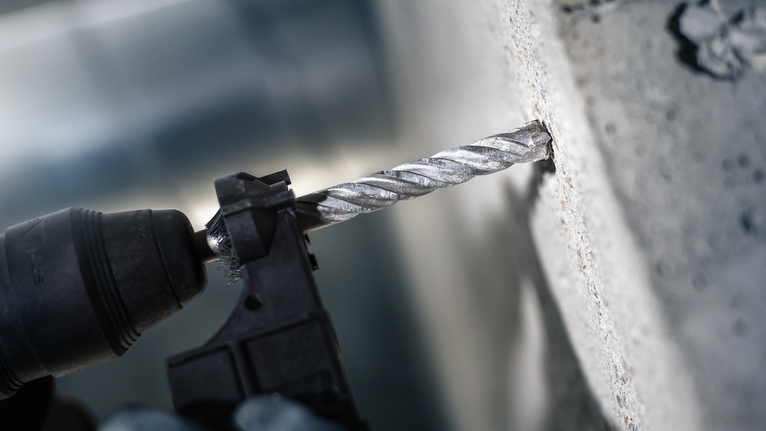 锤钻在混凝土墙上钻孔。