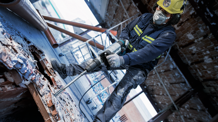 一名身着安全设备的人员在拆除现场钻入混凝土。