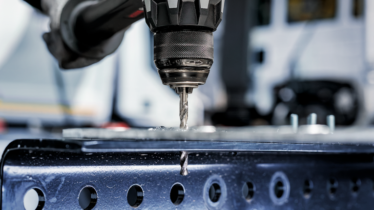 电钻在金属梁上钻孔。