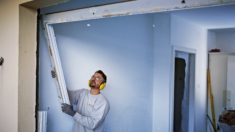 佩戴安全设备的人员正在拆除建筑物内的门框。