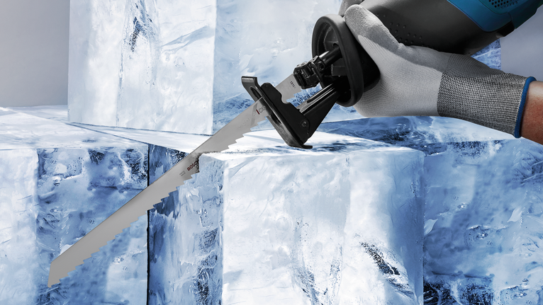 佩戴安全设备的人员使用往复锯切割大冰块。