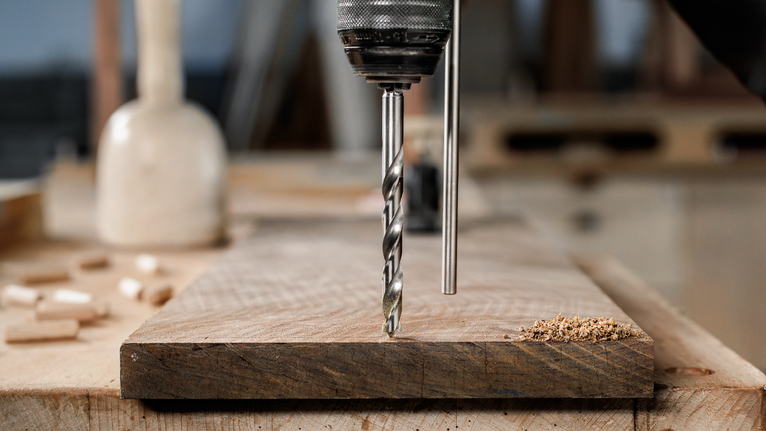 用钻头在工作台上的木板上钻孔。