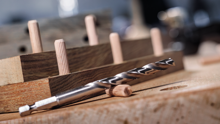 钻头和木钉排列在木制工作台上。