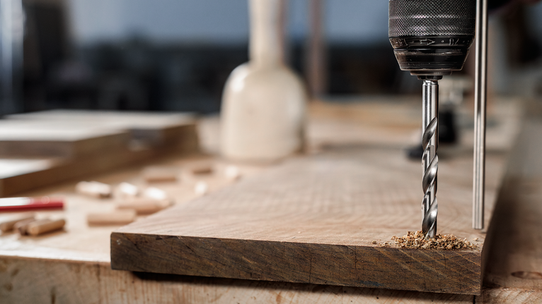 用钻头在工作台上的木板上钻孔。