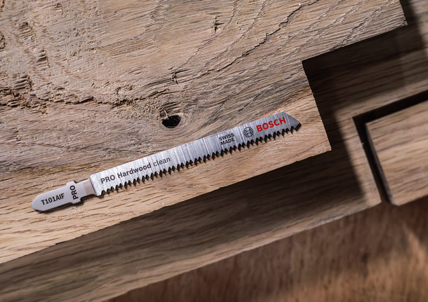 拼图锯刀片放置在带有切口部分的木质表面上。