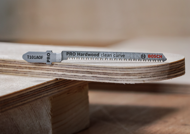 拼图锯刀片放置在光滑弯曲的胶合板边缘上。