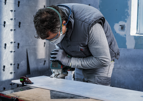 佩戴安全设备的人员使用曲线锯切割木板。