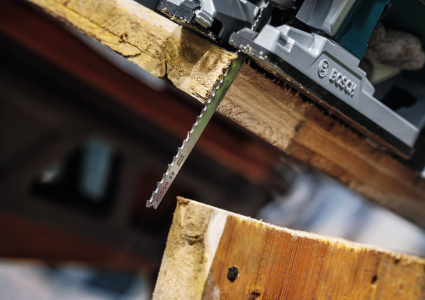 车间里，曲线锯刀片正在切割一块厚木板。