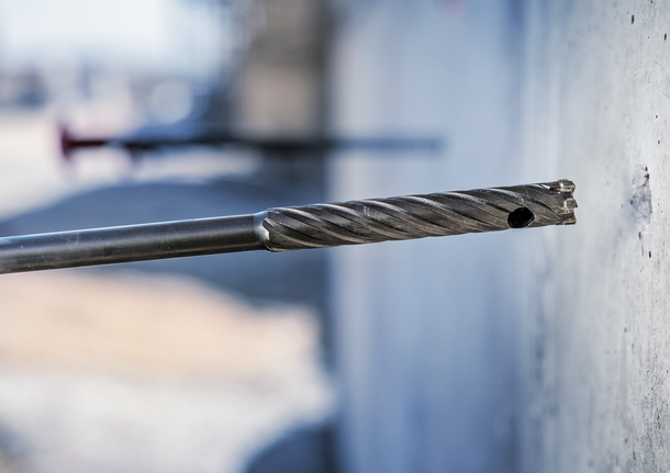 建筑工地上，钻头正在钻入混凝土墙。