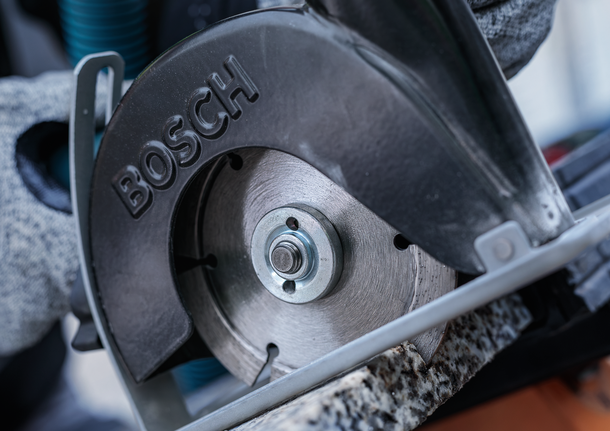 佩戴安全设备的人员用圆锯切割石头。